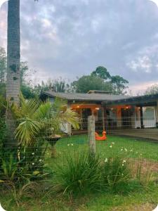 a house with a palm tree in the yard at Casa completa com lareira, piscina compartilhada in Torres