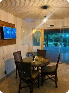 a dining room with a table and chairs and a tv at Casa completa com lareira, piscina compartilhada in Torres