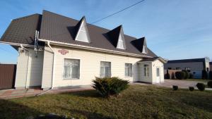 a white house with a black roof with pointed roofs at Фазенда in Bohuslav
