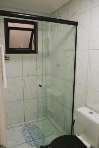 a bathroom with a shower with a tv on the wall at Refúgio completo com Ar condicionado e enxoval in Pelotas +20 photos