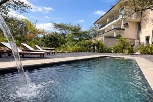 a swimming pool with a fountain in front of a building at Isabel 202! Top studios in Nosara in Nosara