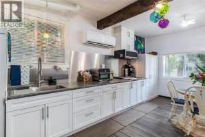 a kitchen with white cabinets and a sink at Nesting Ravens cottage in Nanaimo