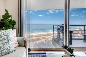 a living room with a couch and a view of the ocean at Cape Town, Blouberg Beachfront Luxury Apt - Kite Beach in Bloubergstrand