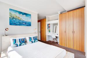 a bedroom with a white bed and a wooden cabinet at Cape Town, Blouberg Beachfront Luxury Apt - Kite Beach in Bloubergstrand +38 photos
