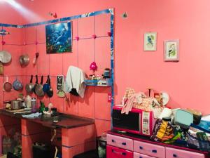 a kitchen with pink walls and a table and a microwave at Casa da BARBIE Praia in Itapipoca