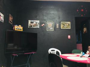 a room with a black wall with a tv and a table at Casa da BARBIE Praia in Itapipoca