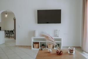 a living room with a table with a television on a wall at Teal Seafront Home in Syvota