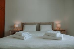 two towels sitting on top of a bed with two lamps at Teal Seafront Home in Syvota