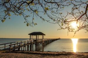 a pier with a gazebo on the beach at sunset at Pousada Trapiche in Pelotas