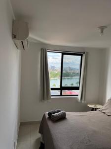 a bedroom with a bed and a large window at Flat aconchegante com vista pro açude in Campina Grande