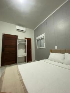 a bedroom with a white bed and a brown door at Refugio tropical icarai in Icaraí +9 photos