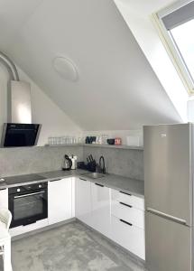 a kitchen with white cabinets and a stainless steel refrigerator at Apartman Amanda - Ohrada in Choťánky +5 photos