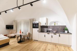 a kitchen with white cabinets and a table in a room at Das Salzamt - Boutique Apartments in Gmunden +13 photos
