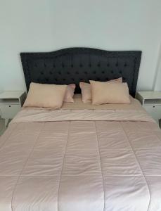 a large bed with a black headboard and pillows at Brisa del mar in Comodoro Rivadavia