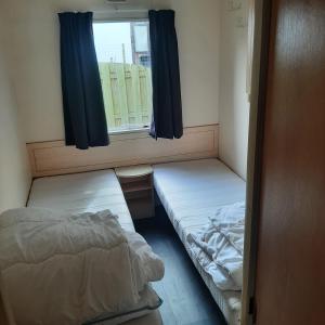 a small room with two beds and a window at Stacaravan in De Pol +19 photos