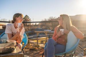 two women sitting on a patio drinking coffee at Timber & Tin G 2Bed 2Bath w Pool & Rooftop Deck in Kanab +101 photos