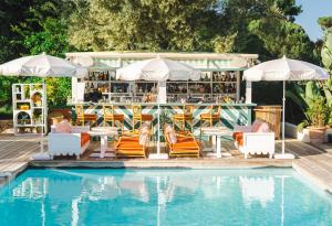 a pool with chairs and tables next to a bar at Hôtel La Tartane Saint-Tropez in Saint-Tropez