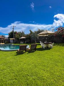 two benches and a table with an umbrella next to a pool at Môzzi Barra Grande in Barra Grande
