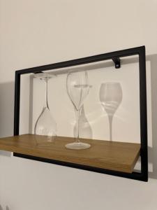 two wine glasses sitting on a wooden shelf at Nathôme 5 in Alençon +2 photos