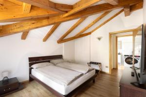 a bedroom with a bed and a tv and wooden ceilings at Appartamento Vittoria in Cles