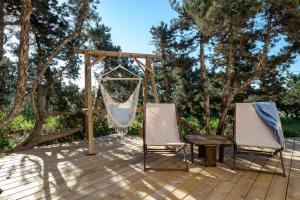 two chairs and a hammock on a deck with trees at Casa Garrover - Calma entre Sabinas in Illes Balears