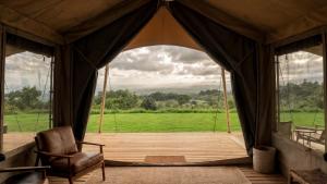 a tent with a chair and a view of a field at Auralta Rio Celeste I Elohi Collection in Rio Celeste