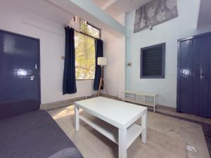 a living room with a white table and a window at Nook Coliving Male Only in Lucknow