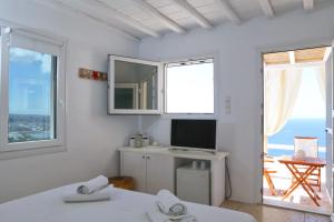 a white room with two beds and a television at La Maison Blanche in Agios Stefanos