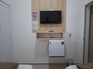 a kitchen with a small refrigerator and a tv on a wall at Hotel Pampa in Nova Santa Medianeira +25 photos