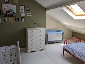 a attic bedroom with a bed and a dresser at Le temps des vacances in Vaudricourt
