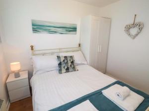 a small bedroom with a bed with white sheets at Sunrise Cottage in Chathill