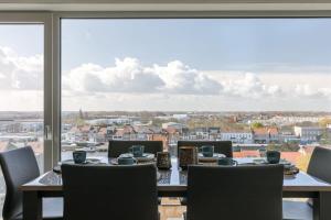 a dining room with a table and chairs and a large window at Casiola - Bright apartment with seaview in Bredene +21 photos