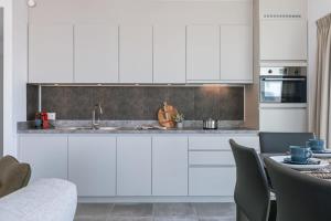 a kitchen with white cabinets and a table with chairs at Casiola - Bright apartment with seaview in Bredene