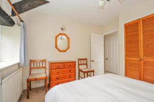 a bedroom with a bed and two chairs and a dresser at Tumrose Cottage in Blisland