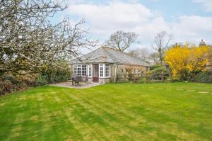 an old stone house with a lawn in front of it at Tumrose Cottage in Blisland