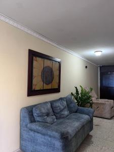 a blue couch in a living room with a painting on the wall at Hotel Danes Barranquilla in Barranquilla