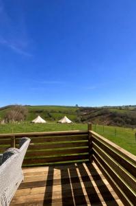 a bench on a deck with tents in a field at Dora's 5 Berth Static with stunning views in Saint Martin