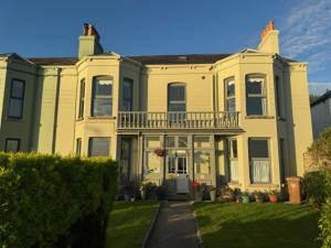 a large yellow house with a balcony on top of it at Dacara Bed & Breakfast in Newcastle
