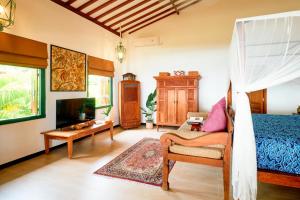 a bedroom with a bed and a tv in a room at Villa Kampung Kecil Beach Front in Kubu