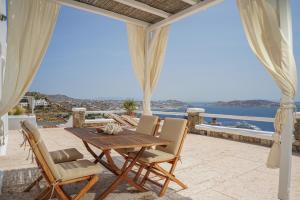 a table and chairs on a patio with a view of the ocean at La Maison Blanche in Agios Stefanos