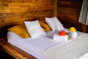 a bed with white sheets and yellow and orange pillows at Le jardin de Védèze in Les Abymes