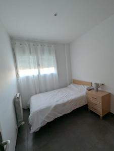 a white bedroom with a bed and a window at Casa Diego in Alcañiz