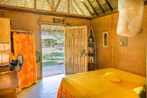 a bedroom with a yellow bed and a window at Charming 1BR Garden Bungalow in Temae