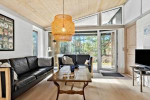a living room with a black leather couch and a table at 2613-Romo-Sneppen-7 in Høm