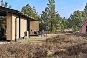 a cabin with a table and an umbrella in the yard at 2613-Romo-Sneppen-7 in Høm