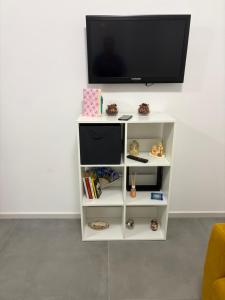 a white book shelf with a television on a wall at sweet rest in Castel Maggiore