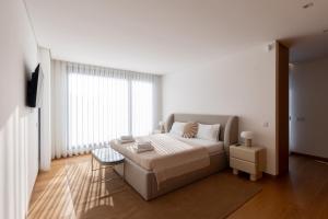 a bedroom with a bed and a large window at Casa Da Luz in Lousada