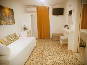 a living room with a white couch and a television at Angeliki Pension in Katapola
