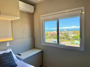 a bedroom with a window with a view of the ocean at Apartamento com vista mar e perto da praia in Tramandaí
