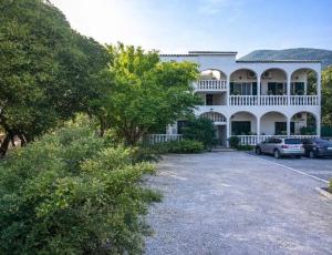 a large white building with cars parked in a parking lot at Terranova beach apartment -Rose in Ipsos